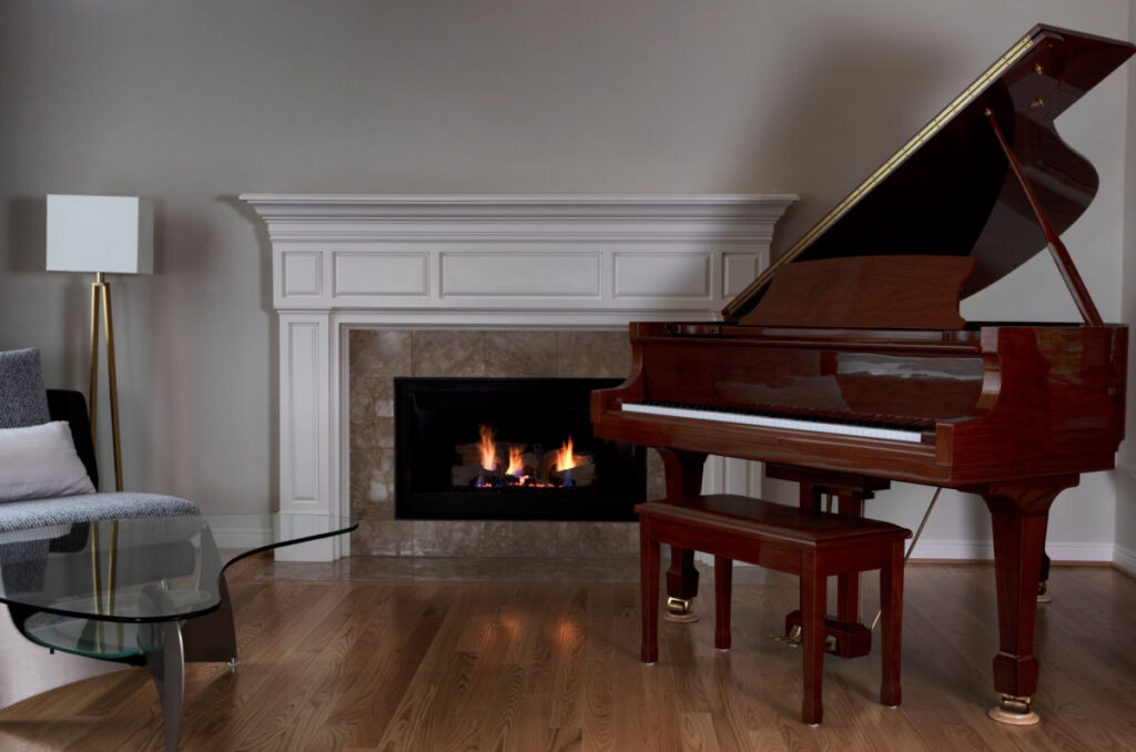 Fireplace insert in newly remodeled home, surrounded by a grand piano, lamp, and chair